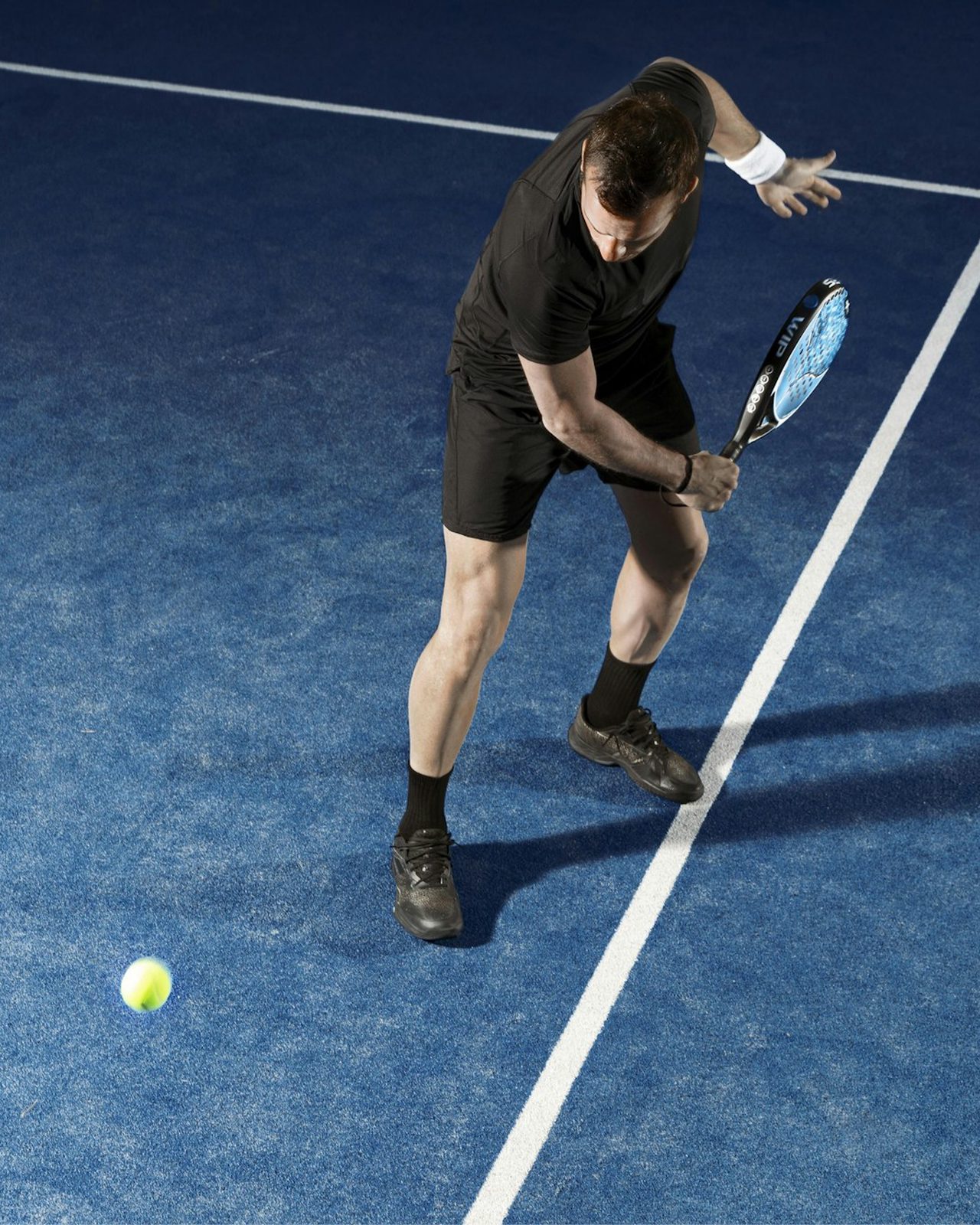 Padel player mid-rally on a blue court